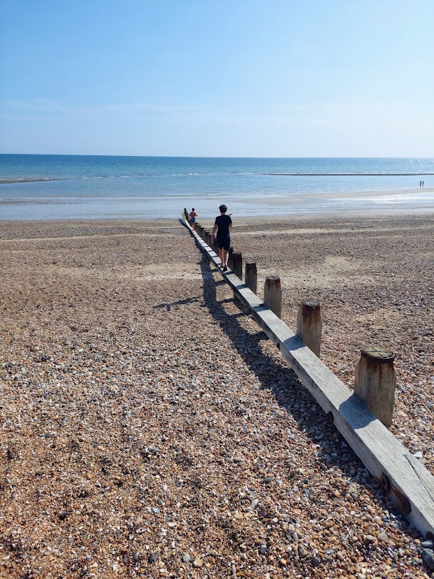 The shingle beach at East Preston with calm blue sea and a wooden groyne